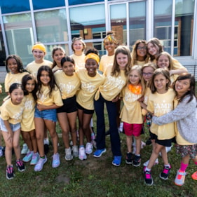 A group of Camp GOTR participants in yellow t-shirts smile and gather